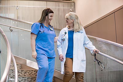 Two nurses walking down a flight of stairs.